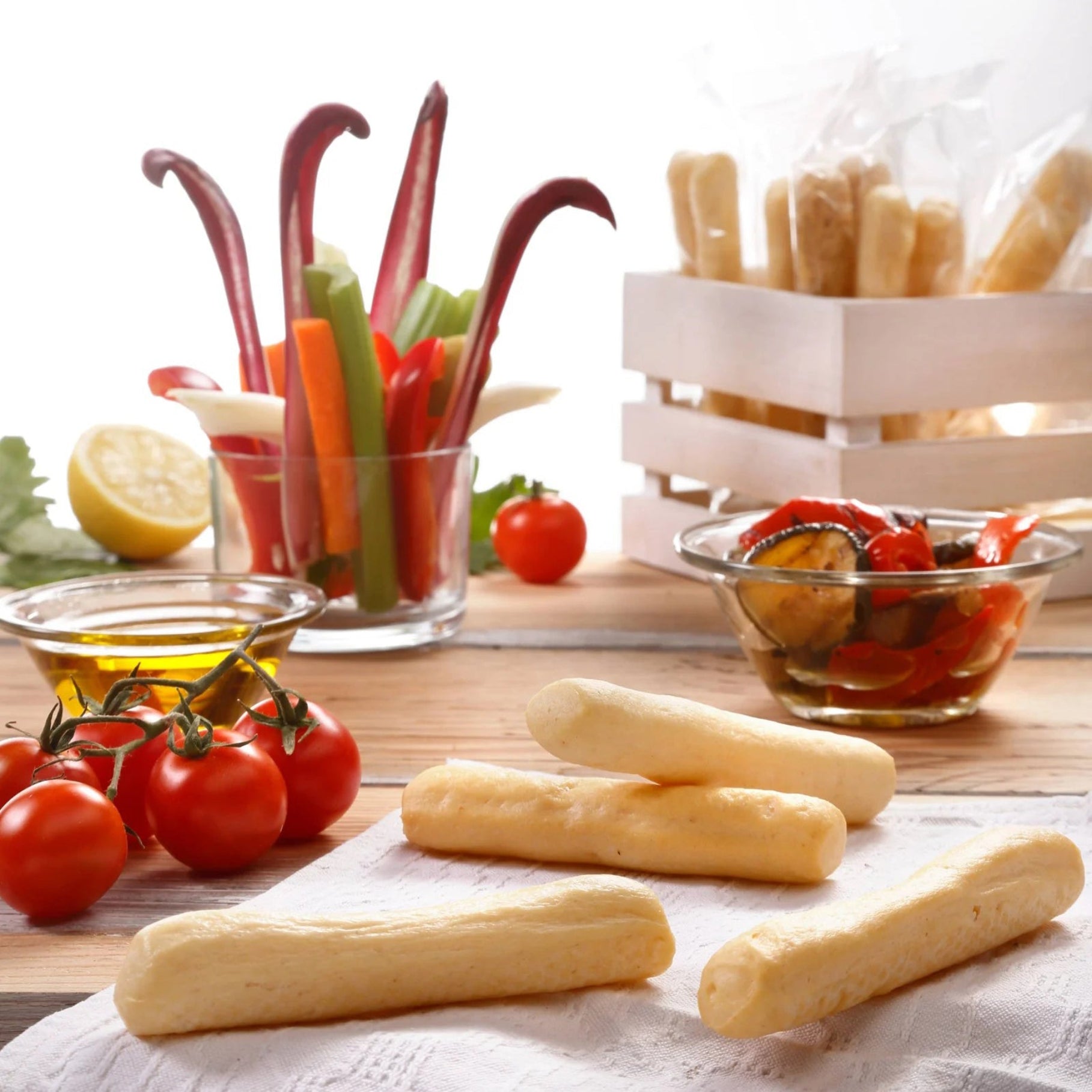 I Macoritti mini breadsticks served with cherry tomatoes, fresh vegetables, and olive oil on wooden table