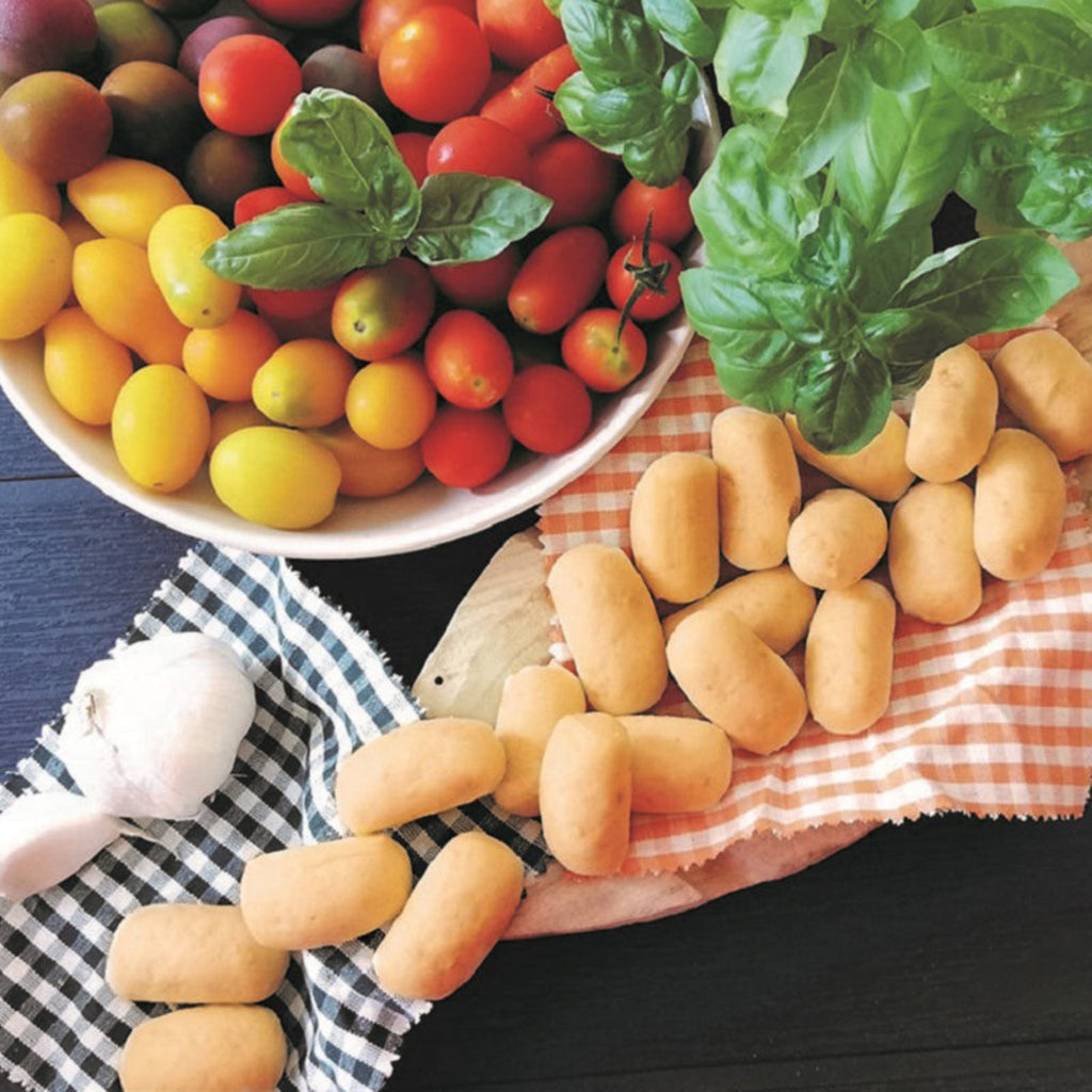 Mini grissini breadsticks with cherry tomatoes, basil leaves, and garlic on table